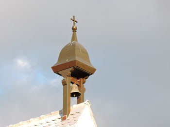 Low angle view of cross and building against sky