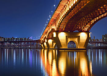 View of illuminated bridge over river at night