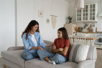 Female friends using laptop while sitting on sofa at home