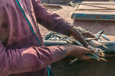 Midsection of man holding fishes outdoors