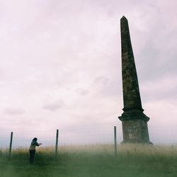 People on grassy field against cloudy sky