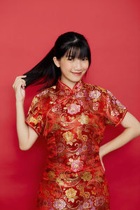 Beautiful young woman smiling against red background