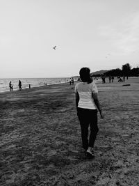 Rear view of people standing on beach