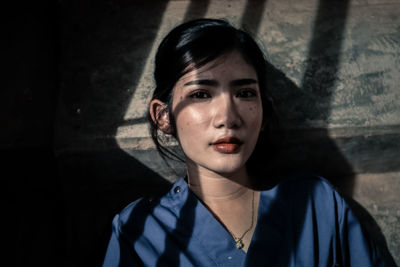 Portrait of young woman against wall