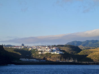 Scenic view of sea by townscape against sky