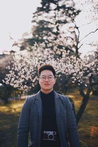 Portrait of young man standing against trees