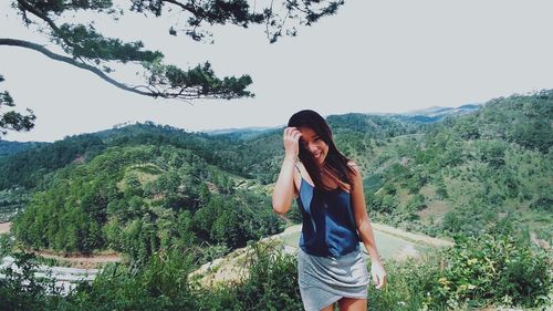 Portrait of happy woman standing against green landscape