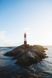 Lighthouse by sea against sky