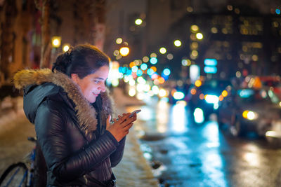 Full length of woman on illuminated city street during winter