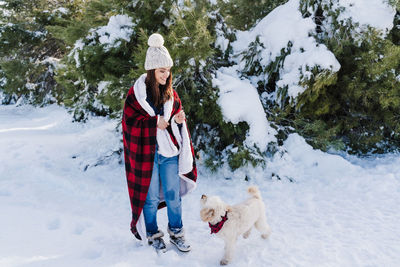 Woman with dog on snowcapped mountain against sky