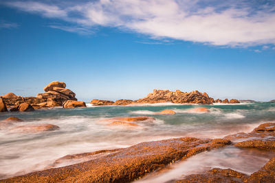 Scenic view of sea by rock formation against sky