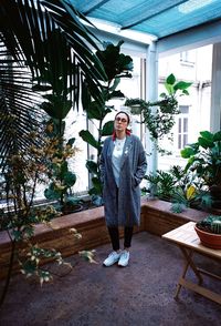 Portrait of man standing against potted plants