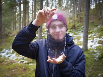 Man holding ice against trees in forest