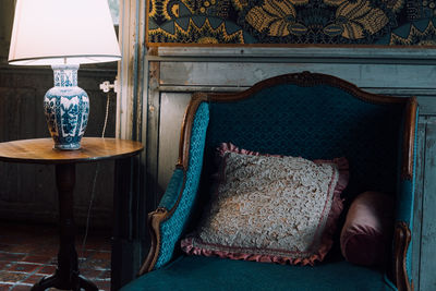 An old armchair with a cushion towards a lamp. pillow and chairs in house