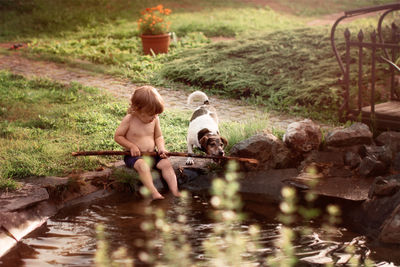 Boy sitting by lake