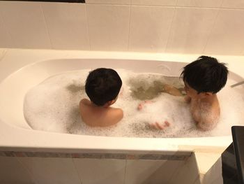 Siblings taking bath in tub at home