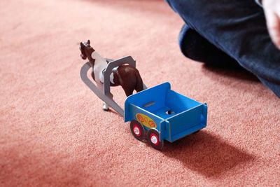 High angle view of person sitting by toy on floor