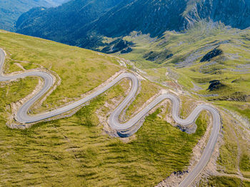 Winding road from high mountain pass, in summer time. aerial view by drone . romania