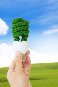 Close-up of woman holding ice cream on field against sky