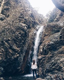 Rear view of woman looking at waterfall on mountain