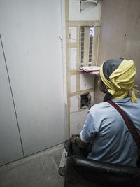 Rear view of man working on wall