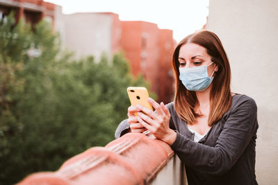 Woman using smart phone while standing in balcony