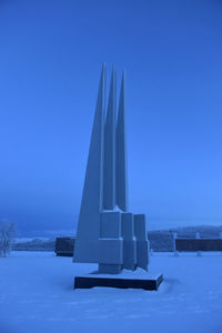 Built structure on snow field against clear blue sky