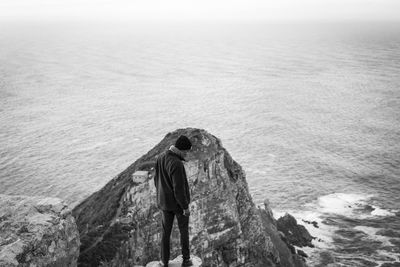 Rear view of woman standing by sea against sky