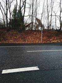 Road by bare trees against sky