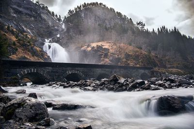 View of waterfall against cloudy sky