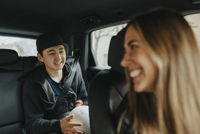 Smiling female coach talking with teenage boy sitting in car