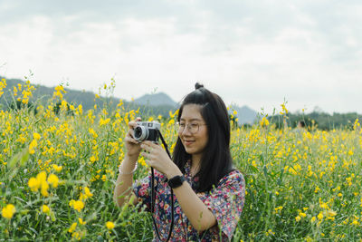 Young woman photographing on field