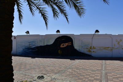 Statue by palm trees against clear sky