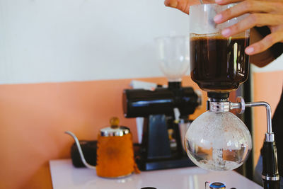 Close-up of hand pouring coffee in cup