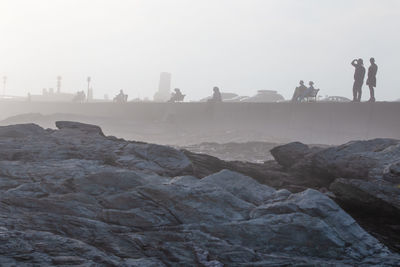 People standing on rock against sky