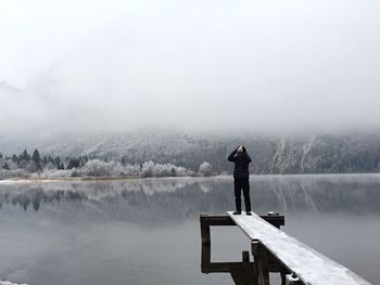 Rear view of man standing on snow against sky