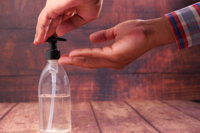 Close-up of hand holding glass bottle on table