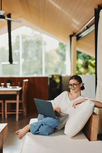 Young woman using mobile phone while sitting at home