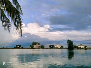 Scenic view of sea by palm trees and houses against sky