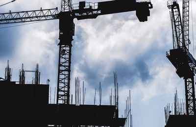 Low angle view of silhouette cranes against sky