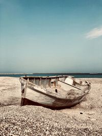 Abandoned boat moored on beach against sky