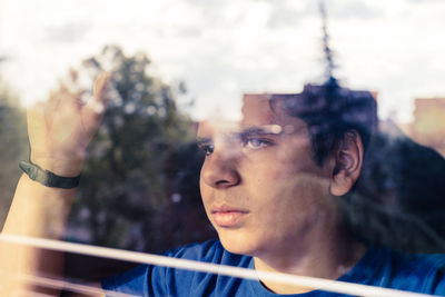 Close-up of boy looking away sitting by window