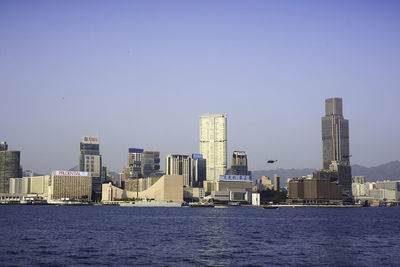Sea by modern buildings against clear sky
