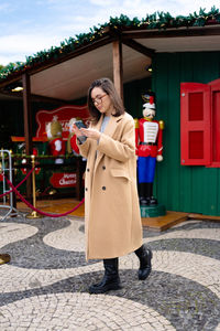 Portrait of young woman standing against building
