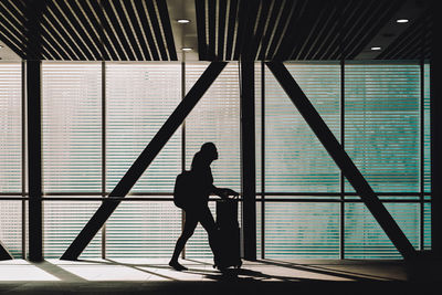 Side view of silhouette man walking against window