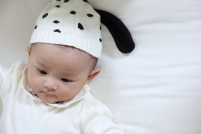 Close-up of baby girl lying on bed