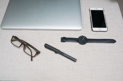 High angle view of mobile phone with laptop and eyeglasses on desk