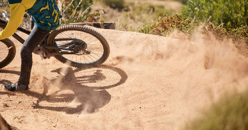 Low section of man riding bicycle on field