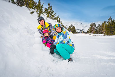 Family build a small snowman next to ski slope. winter holidays in andorra