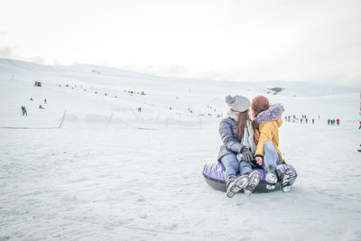 Full length of women sitting on snow during winter